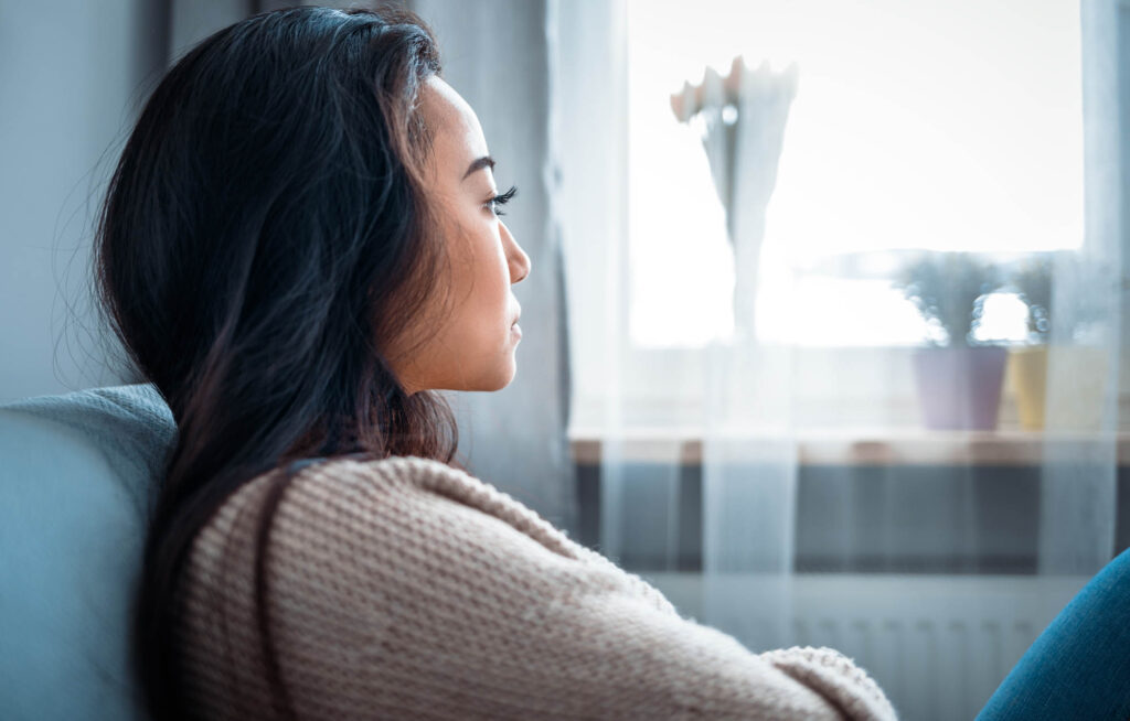 Solentra Wellness | Depressed asian girl sitting on sofa at home and thinking
