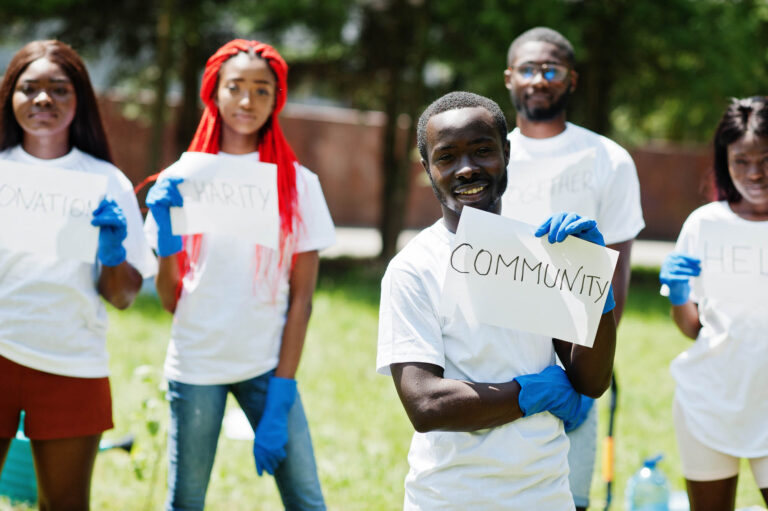 Solentra Wellness | Group of happy african volunteers hold blank board with community sign in park. Africa volunteering, charity, people and ecology concept.