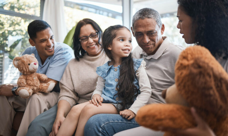 Solentra Wellness | Parents, grandparents and girl with teddy bear on sofa, bonding and smile for game in home living r.