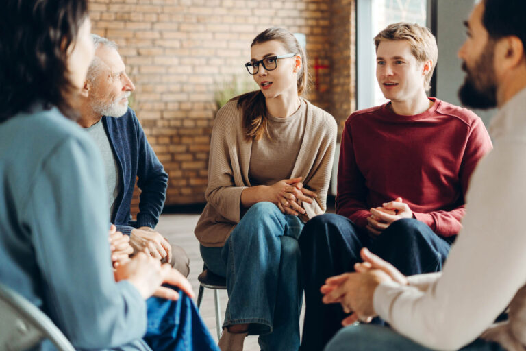 Solentra Wellness | Diverse group of people sharing and discussing in support group meeting